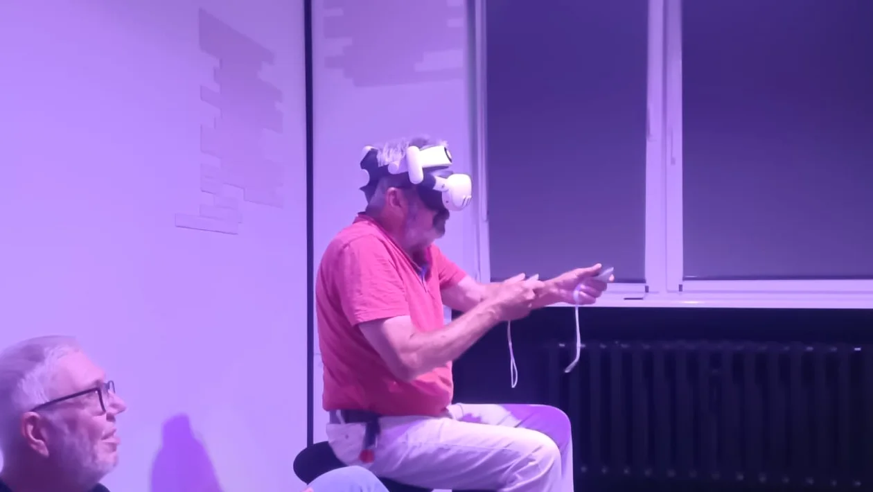 Starszy mężczyzna siedzi w goglach VR i trzyma kontrolery.