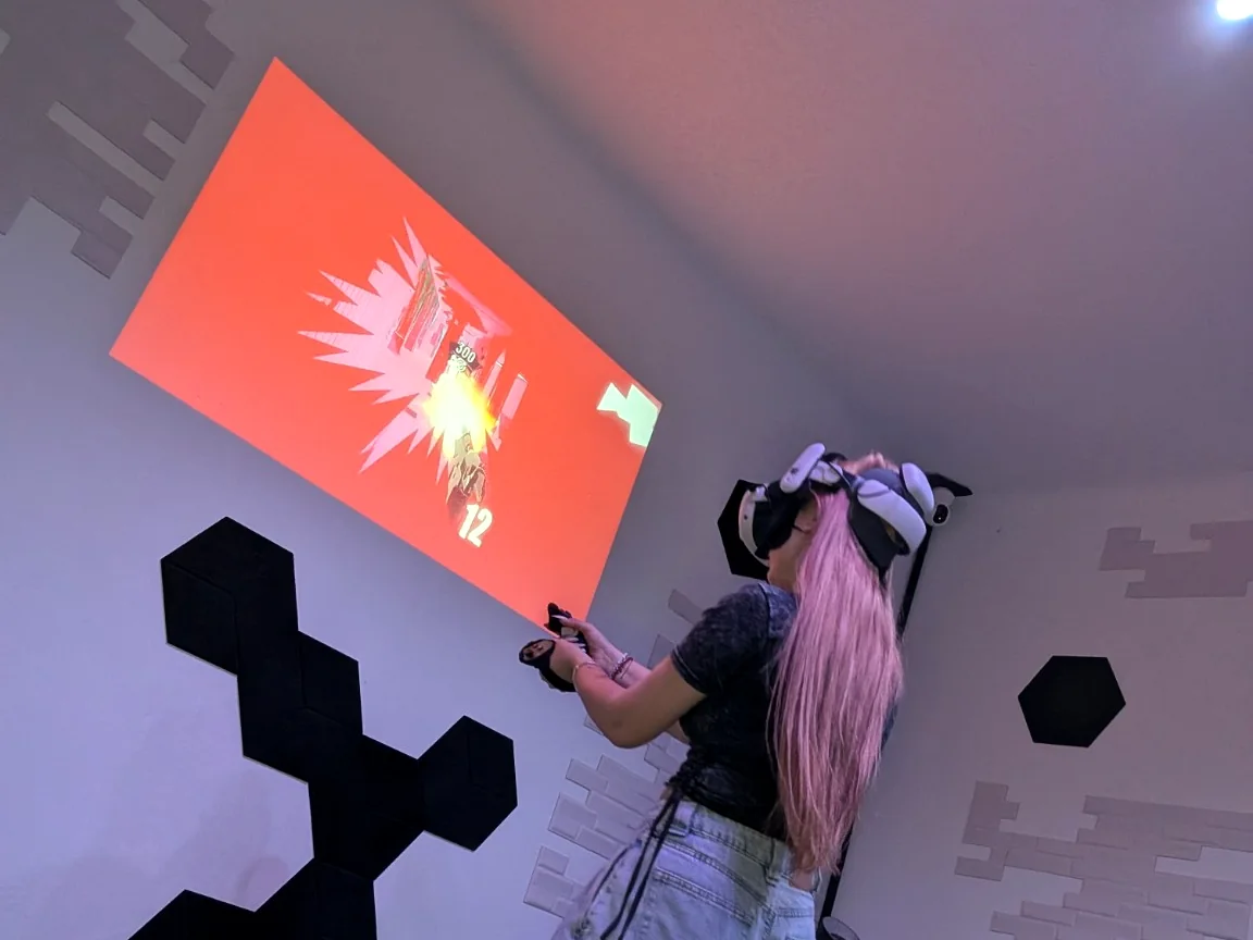Osoba korzystająca z gogli VR w WartaRiver, obok projekcji pokazującej aktualny obraz z gogli.