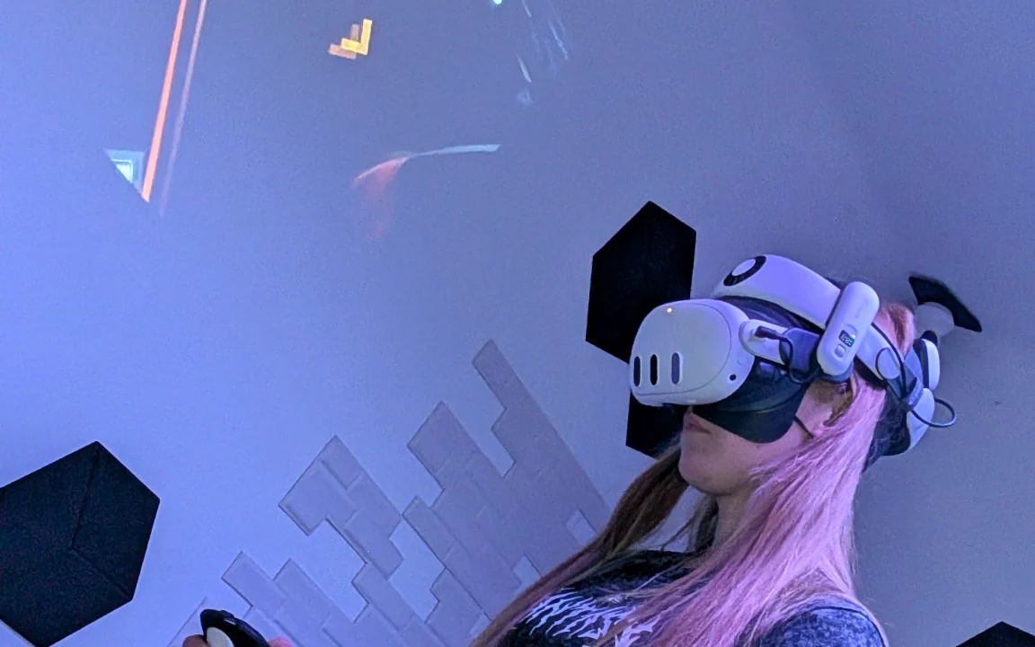 Dorosła osoba korzystająca z gogli VR i kontrolera w sali WartaRiver.