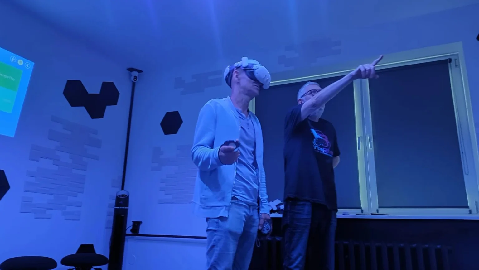 Mężczyzna w goglach VR stoi z wyciągniętą ręką i kontrolerami podczas korzystania z wirtualnej rzeczywistości w studiu WartaRiver.